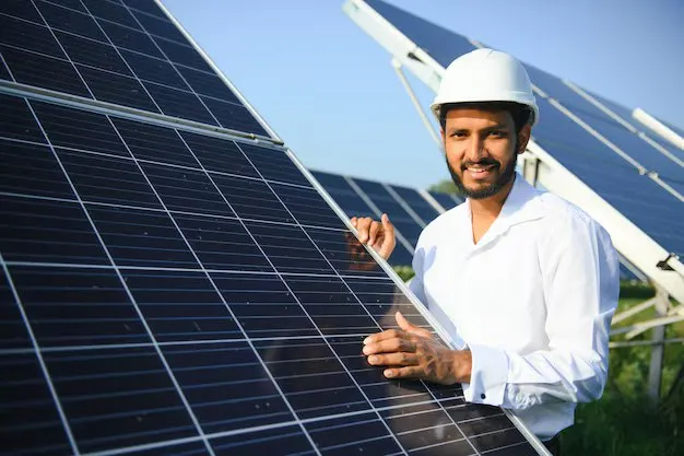 Altura engineer in a hard hat beside solar panels